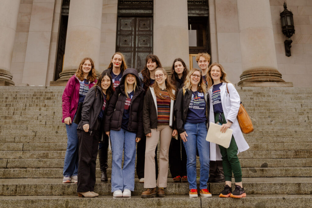 A group of student activists in plain clothes stand on the capitol steps